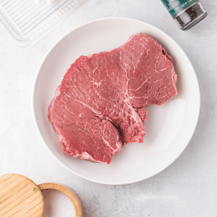 Room temperature
Eye of round steaks resting on a plate at room temperature before air frying