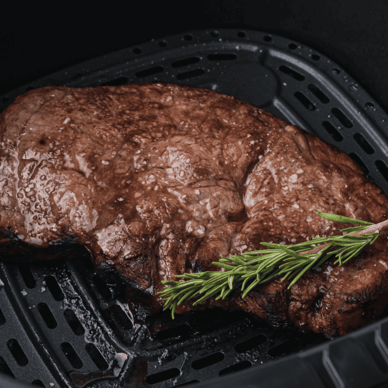 Cooked air fryer round steak resting on a wooden cutting board
