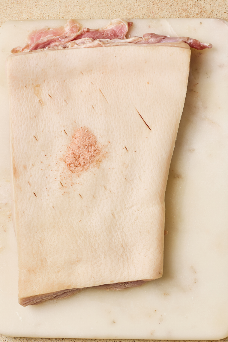 Boiling vinegar water poured over pork belly skin to tighten and dry the surface before cooking.