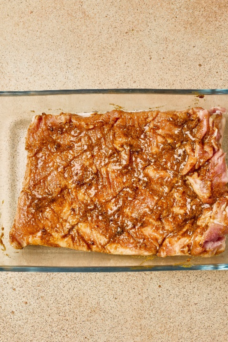 Seasoned pork belly with spice paste spread on the meat side and salt sprinkled over the skin.