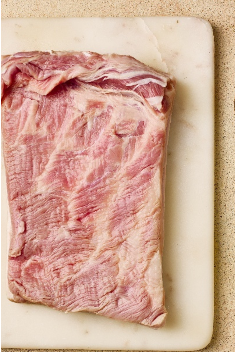 Pork belly wrapped in foil with exposed skin cooking in the air fryer at low temperature.