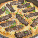 Golden, puffed-up air fryer toad in the hole with browned sausages nestled in crispy Yorkshire pudding batter