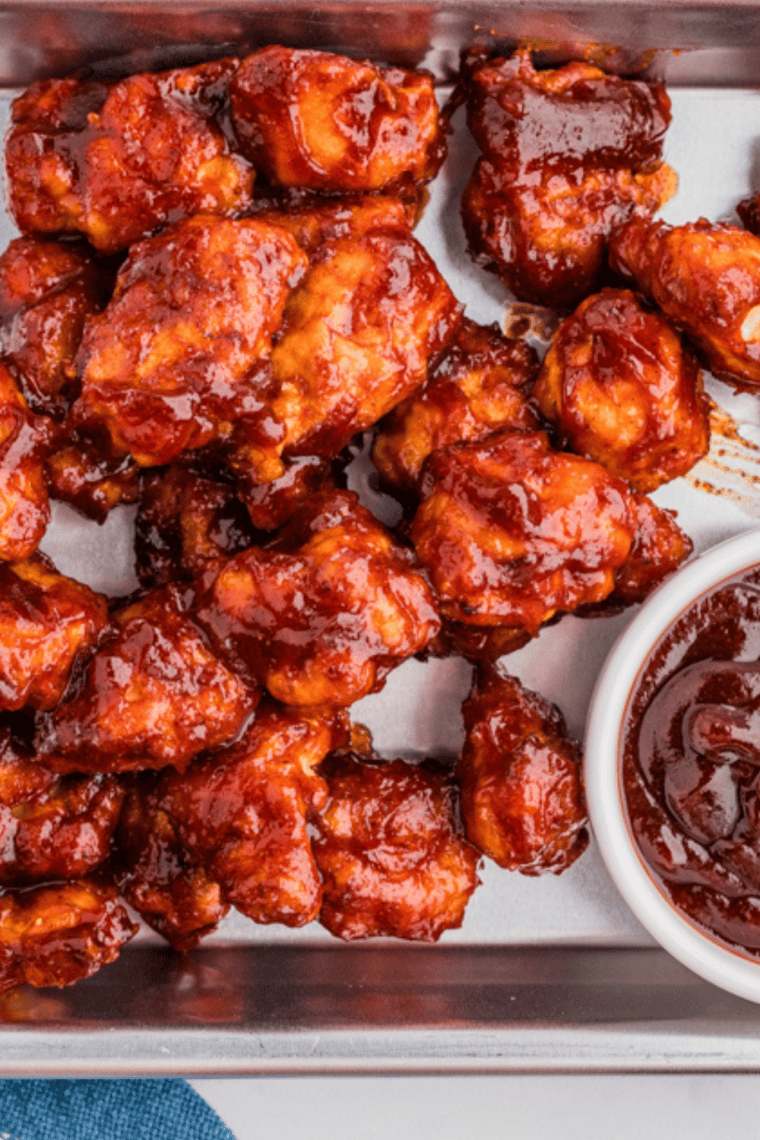 Homemade barbecue sauce being spooned over grilled chicken.