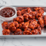 Homemade Burger King BBQ sauce served in a small dipping bowl beside chicken nuggets.