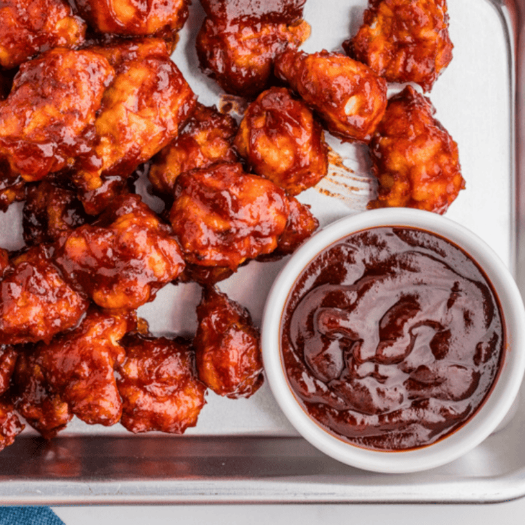 BBQ sauce in a ramekin served with crispy fries and chicken tenders.