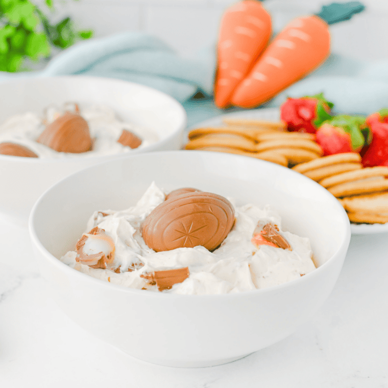 Crushed Cadbury Mini Eggs being folded into whipped cream cheese dip with a spatula.