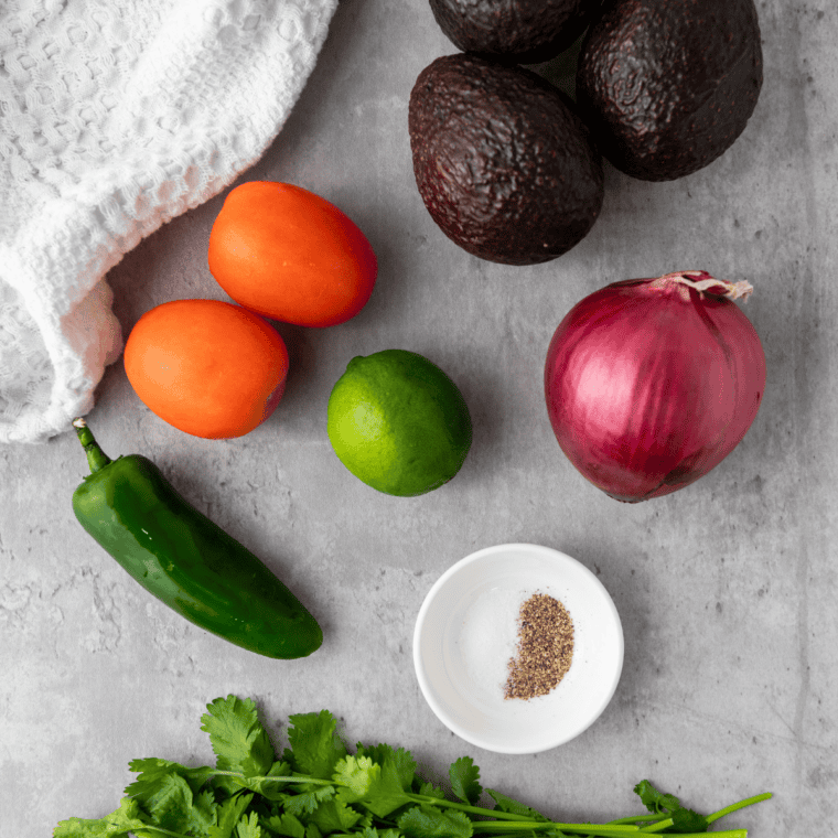 Ingredients needed for Chipotle Guacamole Recipe on kitchen table.
