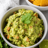 Bowl of Chipotle guacamole made with mashed avocado, lime juice, cilantro, diced onion, and jalape&ntilde;o served with tortilla chips