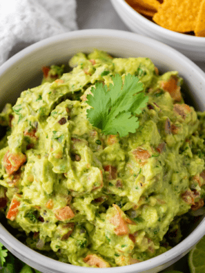 Bowl of Chipotle guacamole made with mashed avocado, lime juice, cilantro, diced onion, and jalape&ntilde;o served with tortilla chips