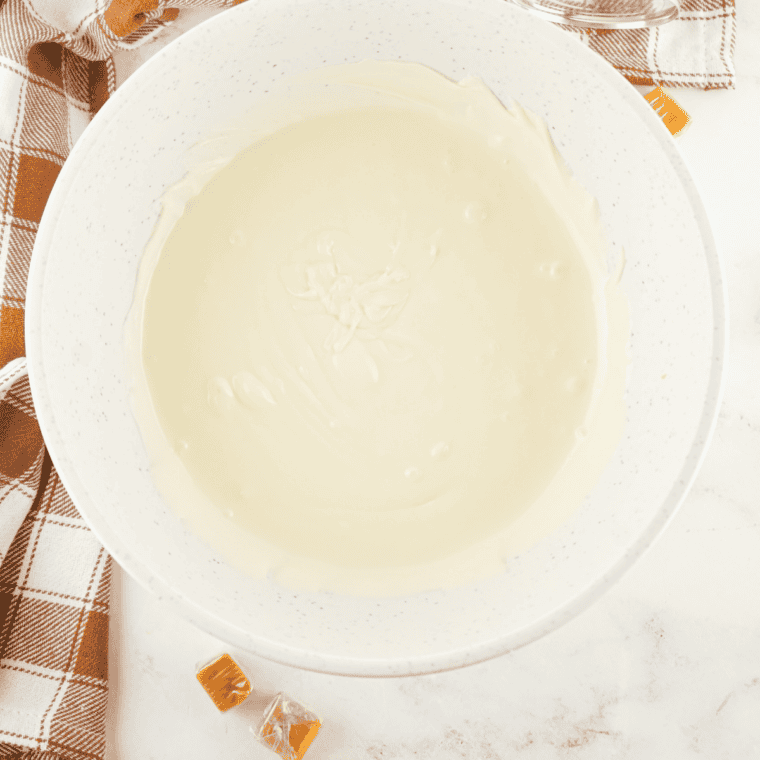 Caramels, white chocolate chips, and butter melting in heavy cream in a saucepan, stirred until thick and glossy