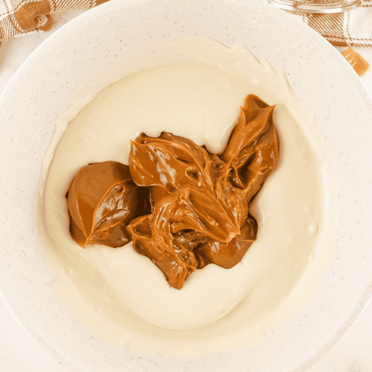 Chocolate chips melting into sweetened condensed milk in a saucepan until smooth and glossy for the fudge base