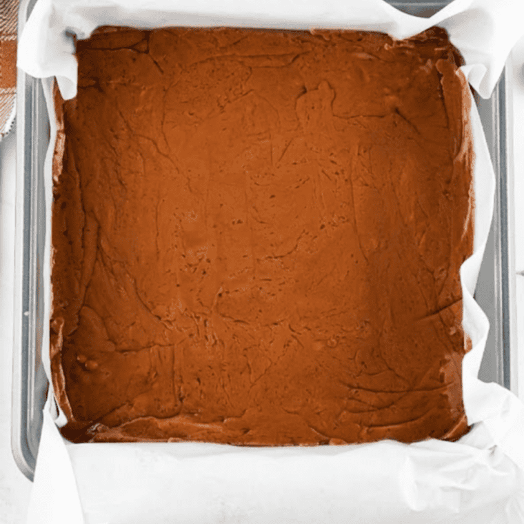 Pan of chocolate caramel marble fudge with caramel swirled across the top, ready to chill until firm