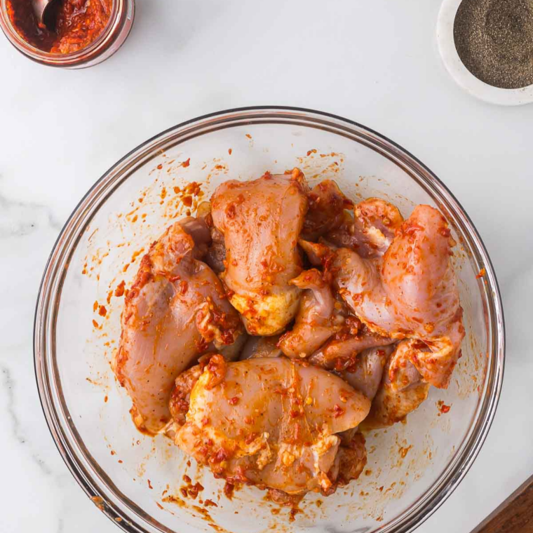 lose-up of mesquite spice rub being sprinkled over chicken.