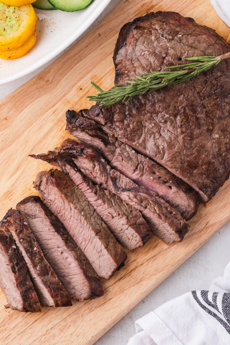 Rustic jar of mesquite seasoning next to grilled meats on cutting board