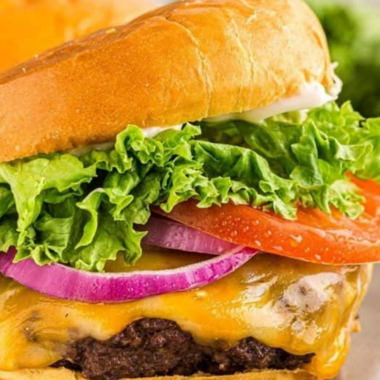 Smash burger cheeseburger with American cheese, pickles, and onions on a toasted bun, styled like fast-food presentation.