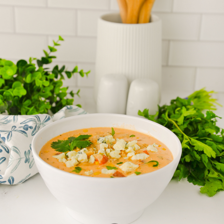 Bowl of Crock Pot Buffalo Chicken Chili topped with shredded cheese, sour cream, and green onions