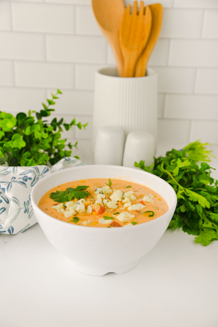 Bowl of Crock Pot Buffalo Chicken Chili topped with shredded cheddar cheese, sour cream, and green onions