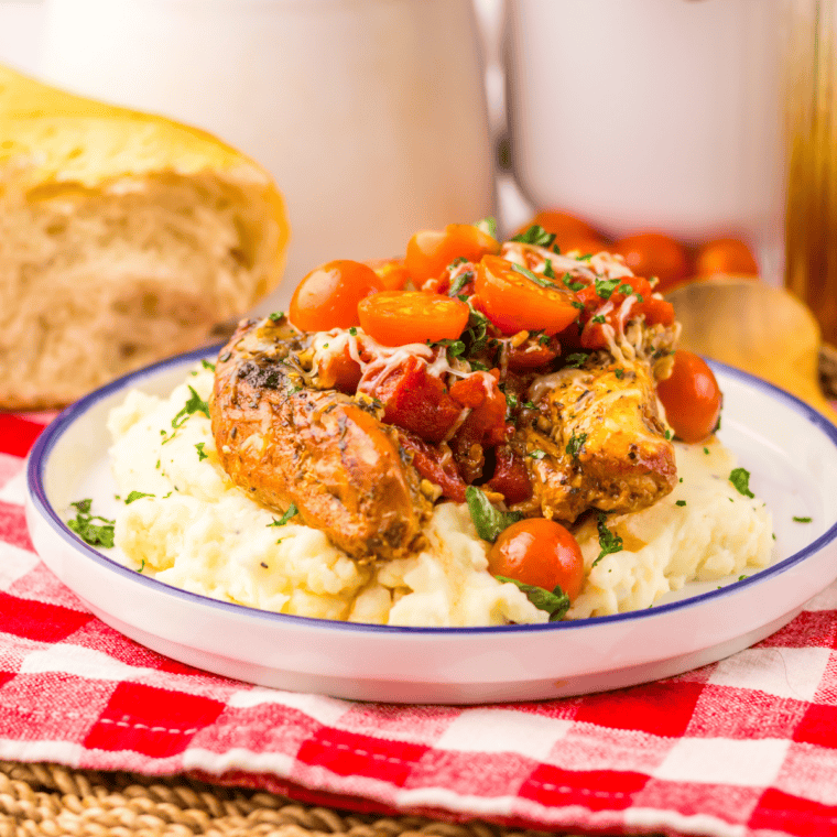 Slow cooker bruschetta chicken topped with diced tomatoes, basil, and balsamic glaze served over chicken breasts