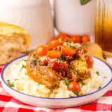 Slow cooker bruschetta chicken topped with fresh tomatoes, basil, and melted mozzarella in a white bowl