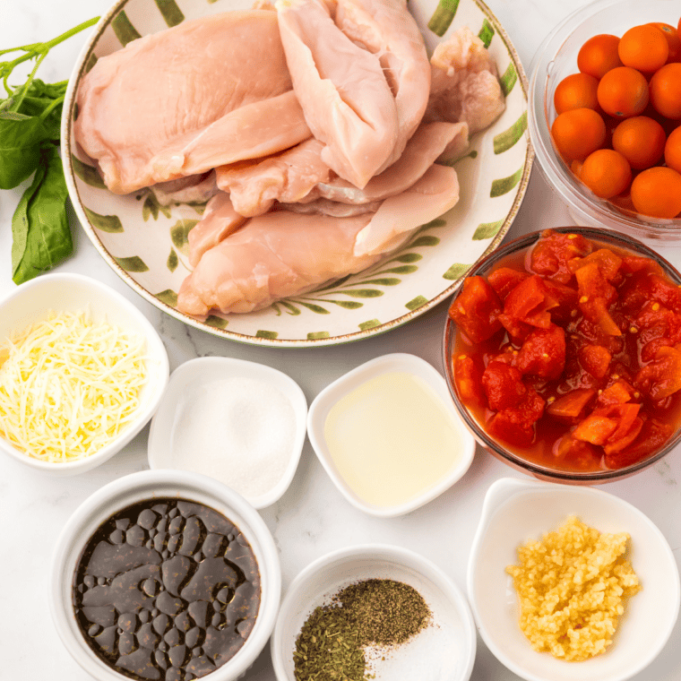 Crockpot Bruschetta Chicken ingredients on kitchen counter with colorful plates.
