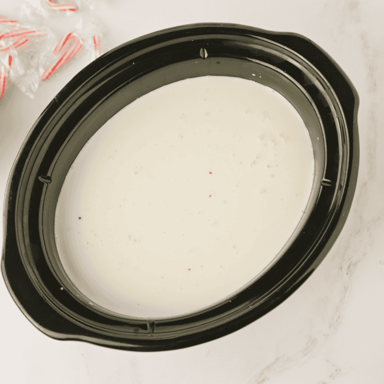 Pouring milk, cream, chocolate chips, and peppermint extract into a slow cooker