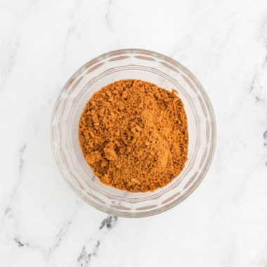 Small glass bowl filled with homemade chili seasoning mix made with paprika, chili powder, cumin, and garlic powder.