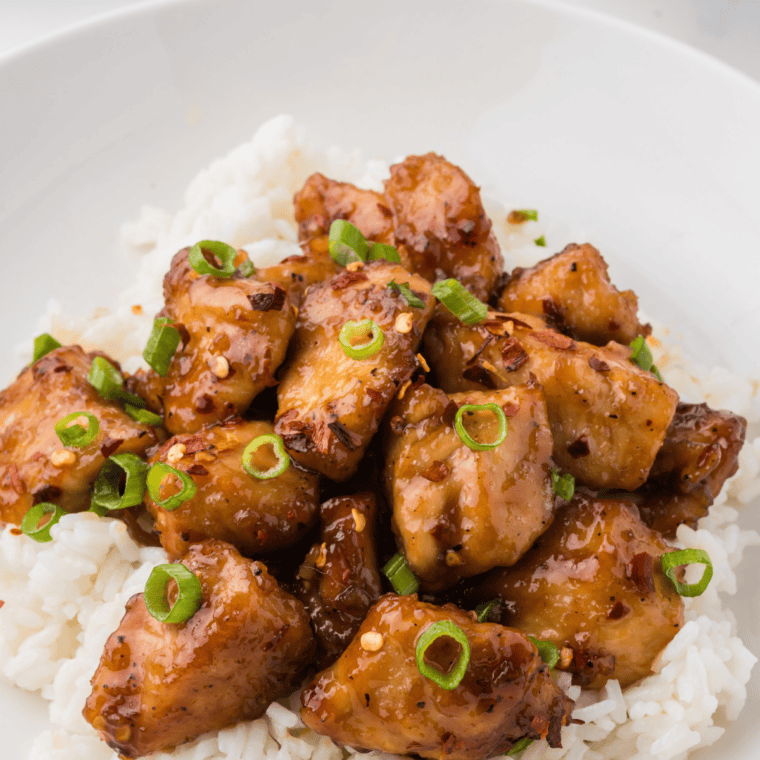 Juicy chicken coated in sticky honey garlic sauce with a glossy caramelized finish and a sprinkle of sesame seeds on top.