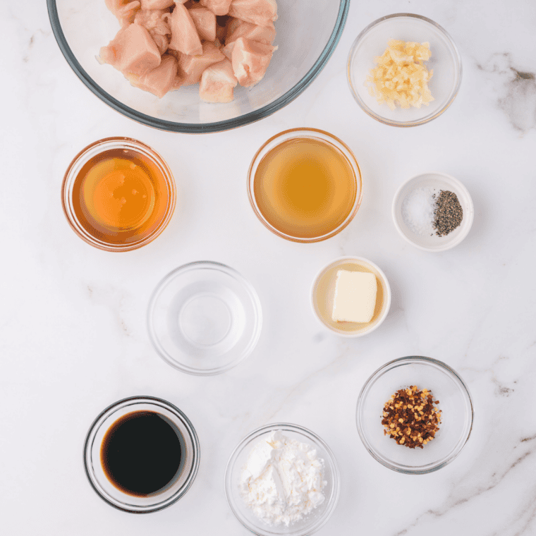 Ingredients for honey garlic sauce including honey, soy sauce, fresh garlic, rice vinegar, water, cornstarch, and optional brown sugar, ginger, and red pepper flakes laid out on a kitchen counter.