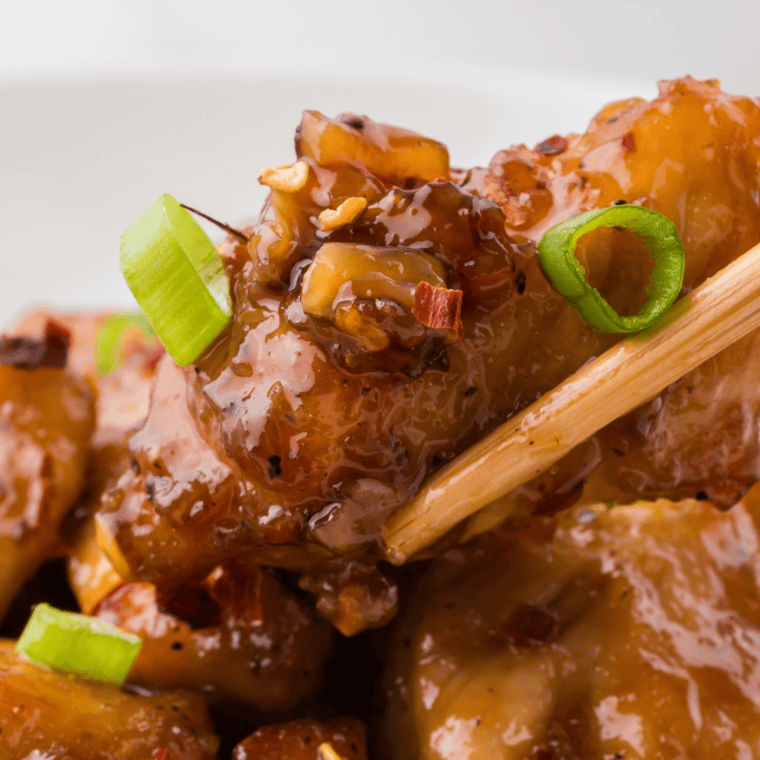 Honey garlic sauce glazed over juicy chicken with glossy caramelized coating and sesame seeds garnish