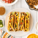 Homemade McCormick taco seasoning copycat in a small glass jar with a measuring spoon on a wooden board
