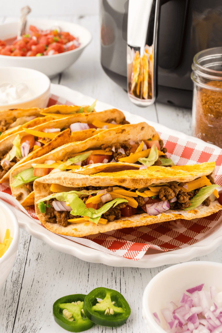 Bowl of DIY taco seasoning mix next to taco meat and tortillas on a rustic table