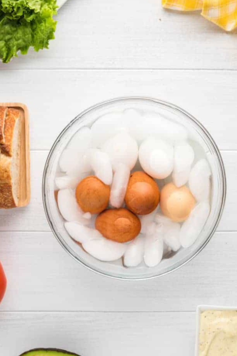 Transfering Ninja Crispi hard boiled eggs into an ice water bath to cool before peeling