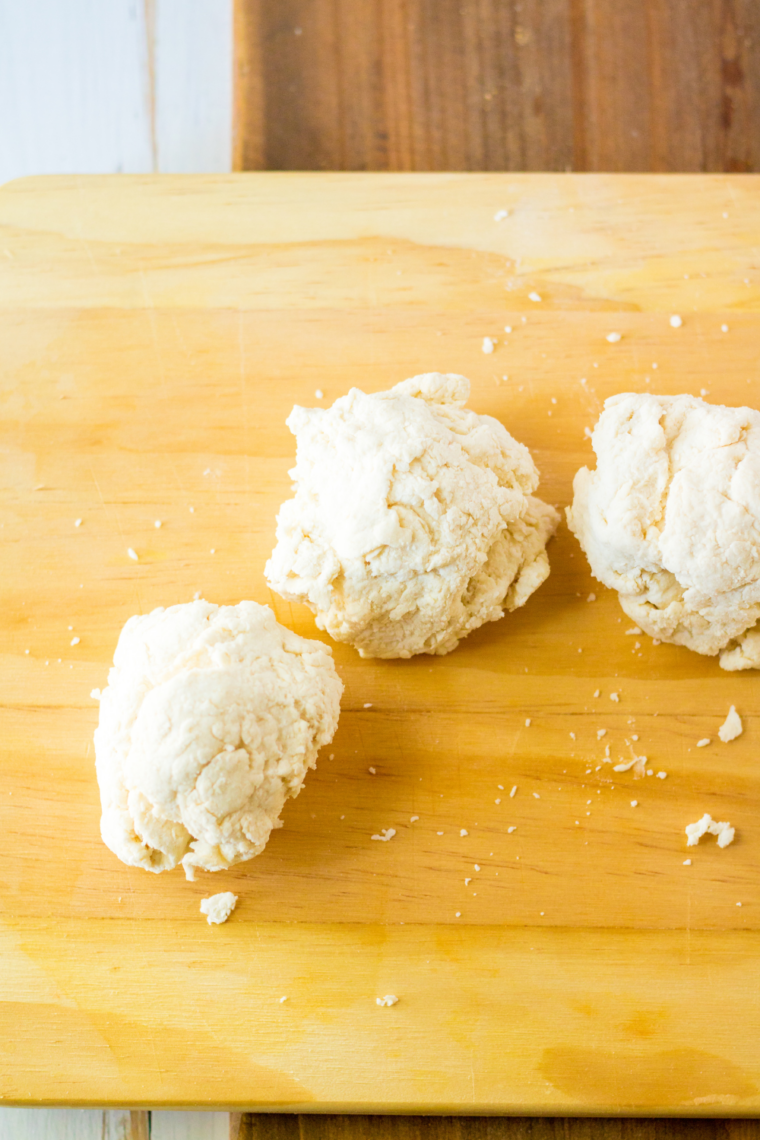 Rolling dough into ropes and shaping into bagels, then placing them on a prepared baking sheet.