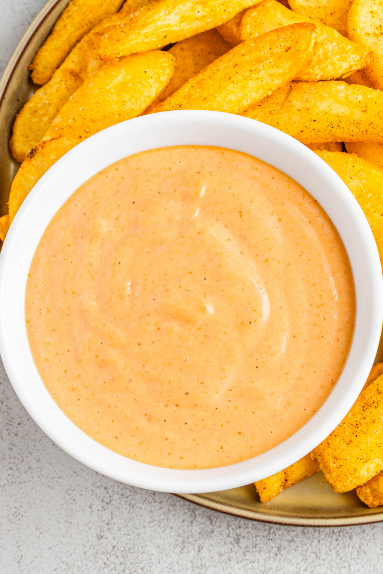 Close-up of homemade Popeyes-style dipping sauce in a small white bowl with fries