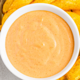 Close-up of homemade Popeyes-style dipping sauce in a small white bowl with fries