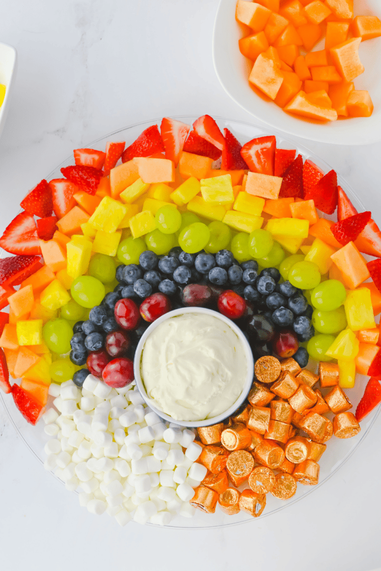 Easy rainbow fruit platter with strawberries, cantaloupe, pineapple, green grapes, blueberries, and purple grapes