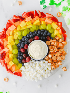 Rainbow fruit tray with marshmallow clouds and Rolo gold arranged on a round serving tray for St. Patrick's Day