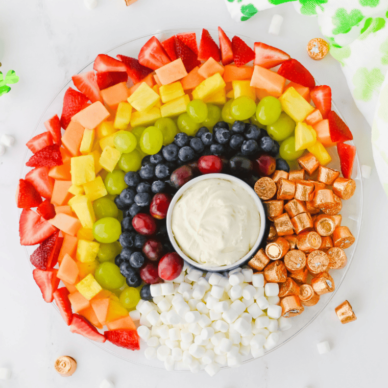 Rainbow fruit tray with marshmallow clouds and Rolo gold on a round platter for St. Patrick's Day