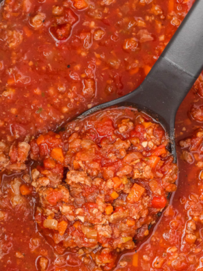 Slow cooker bolognese sauce in a bowl with pasta and grated parmesan