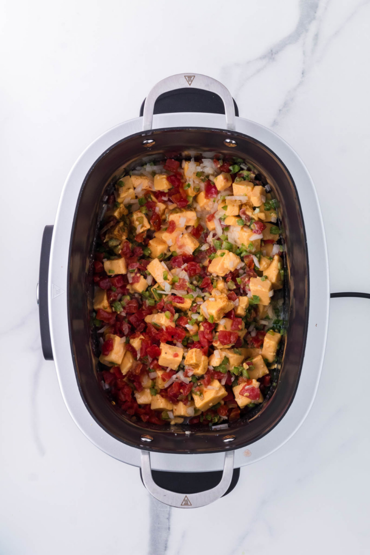 Velveeta Rotel and cheeses added to slow cooker and stirred