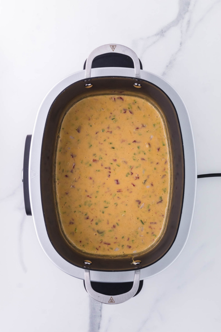 Queso cooking in slow cooker stirred every 30 minutes until smooth