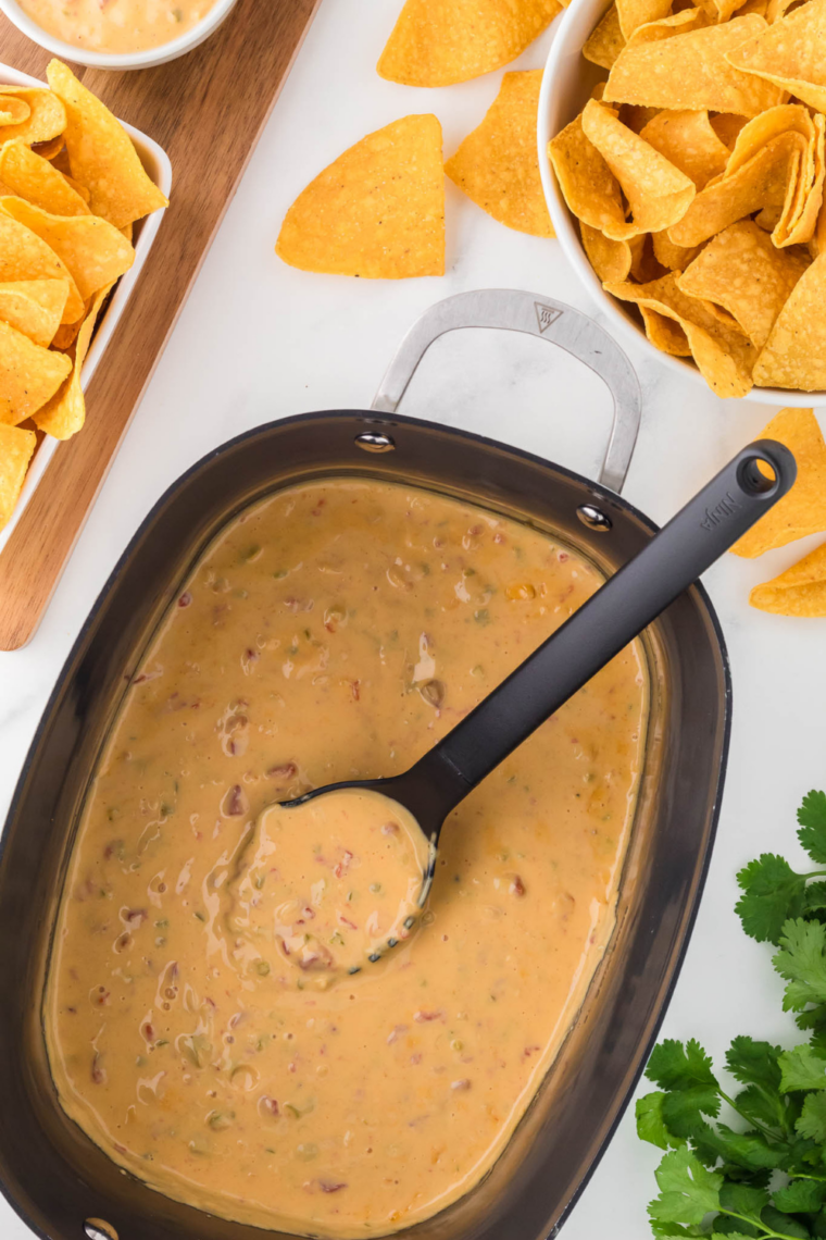 Slow cooker Velveeta queso melted into creamy cheesy dip served warm with tortilla chips