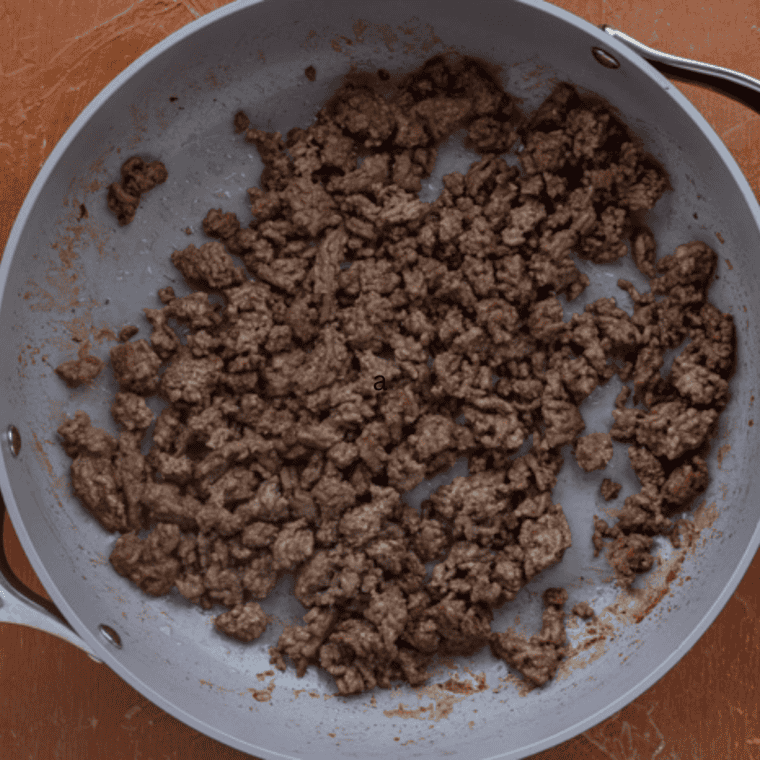 Preheat and Brown
Ground venison browning with diced onion and seasonings in a cast iron skillet