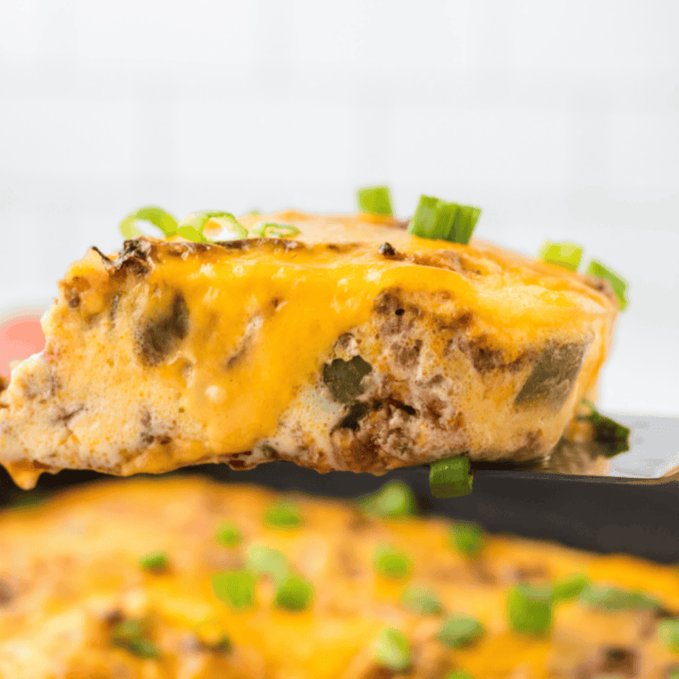 Cheesy venison casserole in a cast iron skillet with melted cheddar bubbling on top
