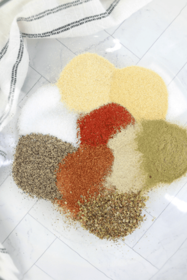 Measuring dried spices into a small mixing bowl over parchment paper for easy cleanup.