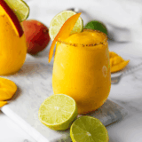 frozen mango margarita in a glass with salt rim and lime wedge