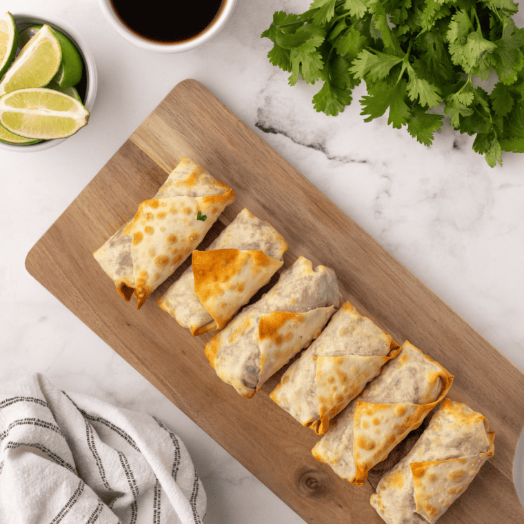A plate of crispy air fryer birria egg rolls served with consomm&eacute;.