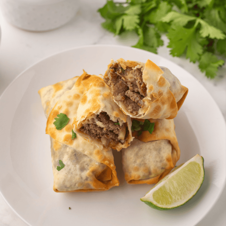 Close-up of crispy beef birria egg rolls showing the cheesy shredded beef filling