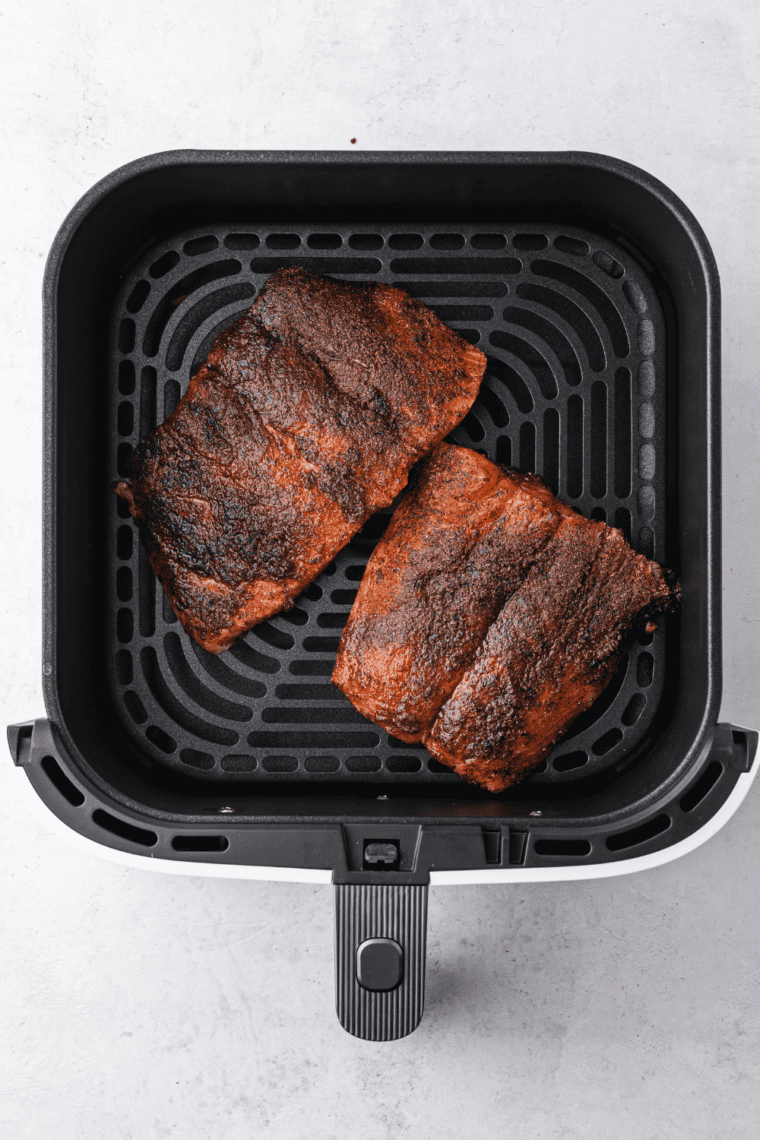Salmon fillets cooking in the air fryer basket until flaky and opaque