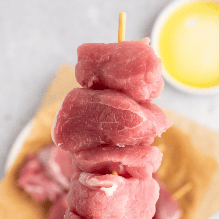 Holding a jerk pork kebab showing juicy seasoned pork tenderloin chunks.